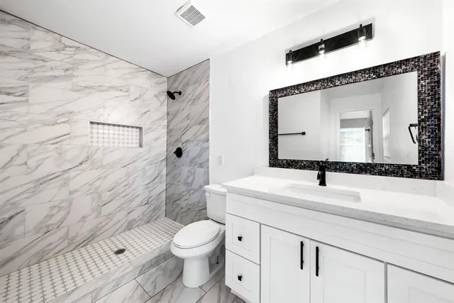 a bathroom with a sink a toilet and shower