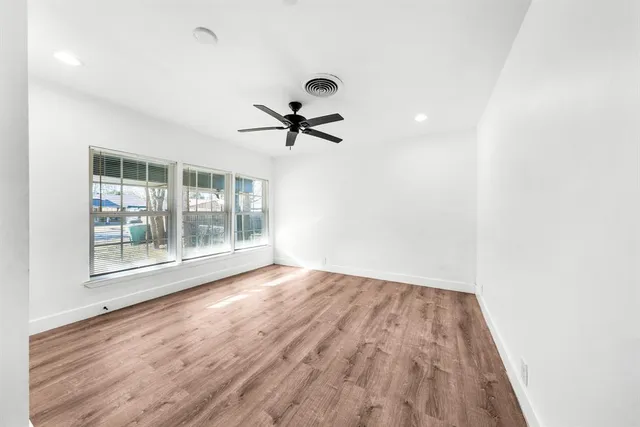 a view of empty room with wooden floor and fan