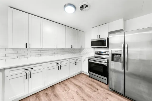 a kitchen with granite countertop white cabinets and stainless steel appliances