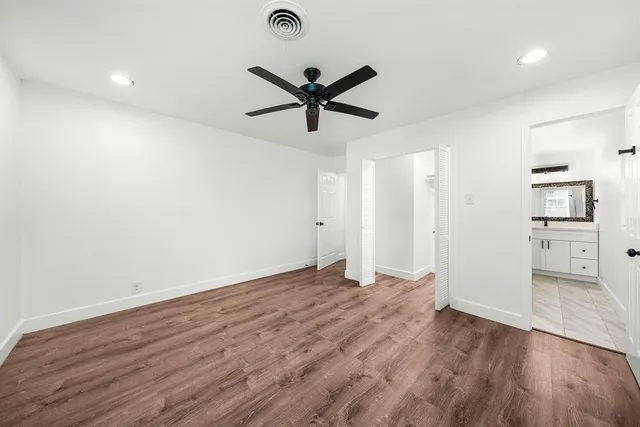 a view of empty room with wooden floor and ceiling fan