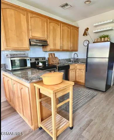 a kitchen with stainless steel appliances granite countertop a refrigerator a stove a sink and a microwave