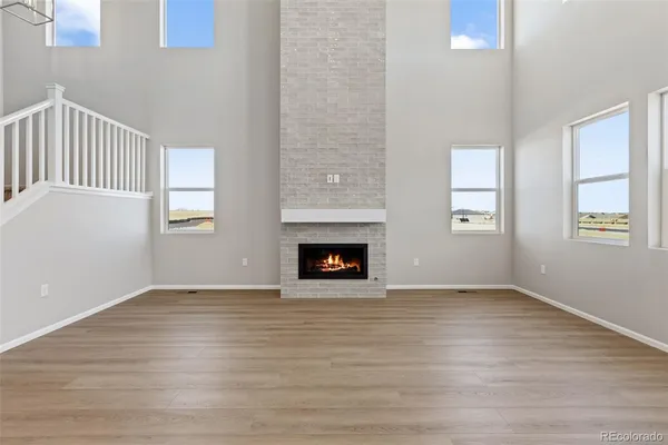 a view of an empty room with wooden floor fireplace and a window