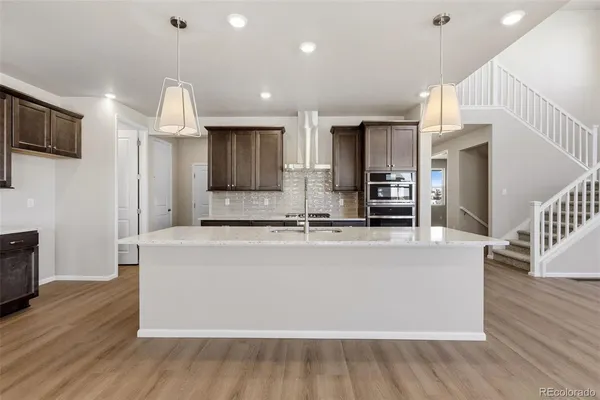 a large kitchen with stainless steel appliances a large counter top a wooden floor a fireplace and a window