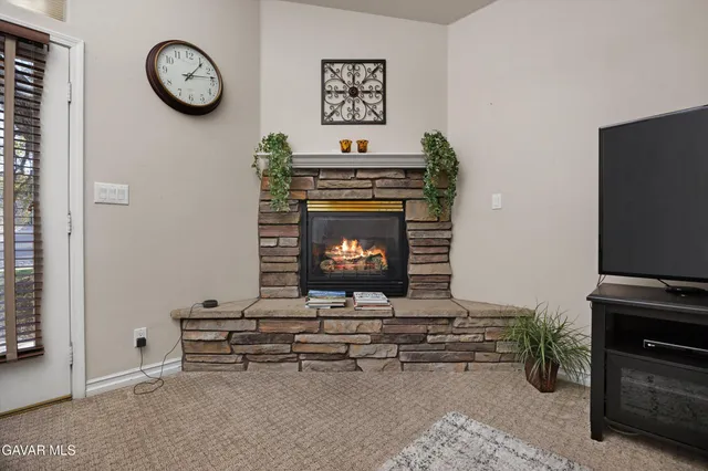 a view of a dining room and livingroom with furniture a rug a fireplace and a clock