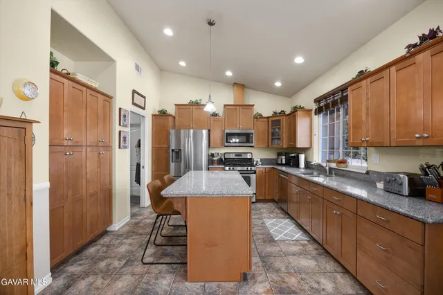 a kitchen with stainless steel appliances granite countertop table chairs sink and cabinets
