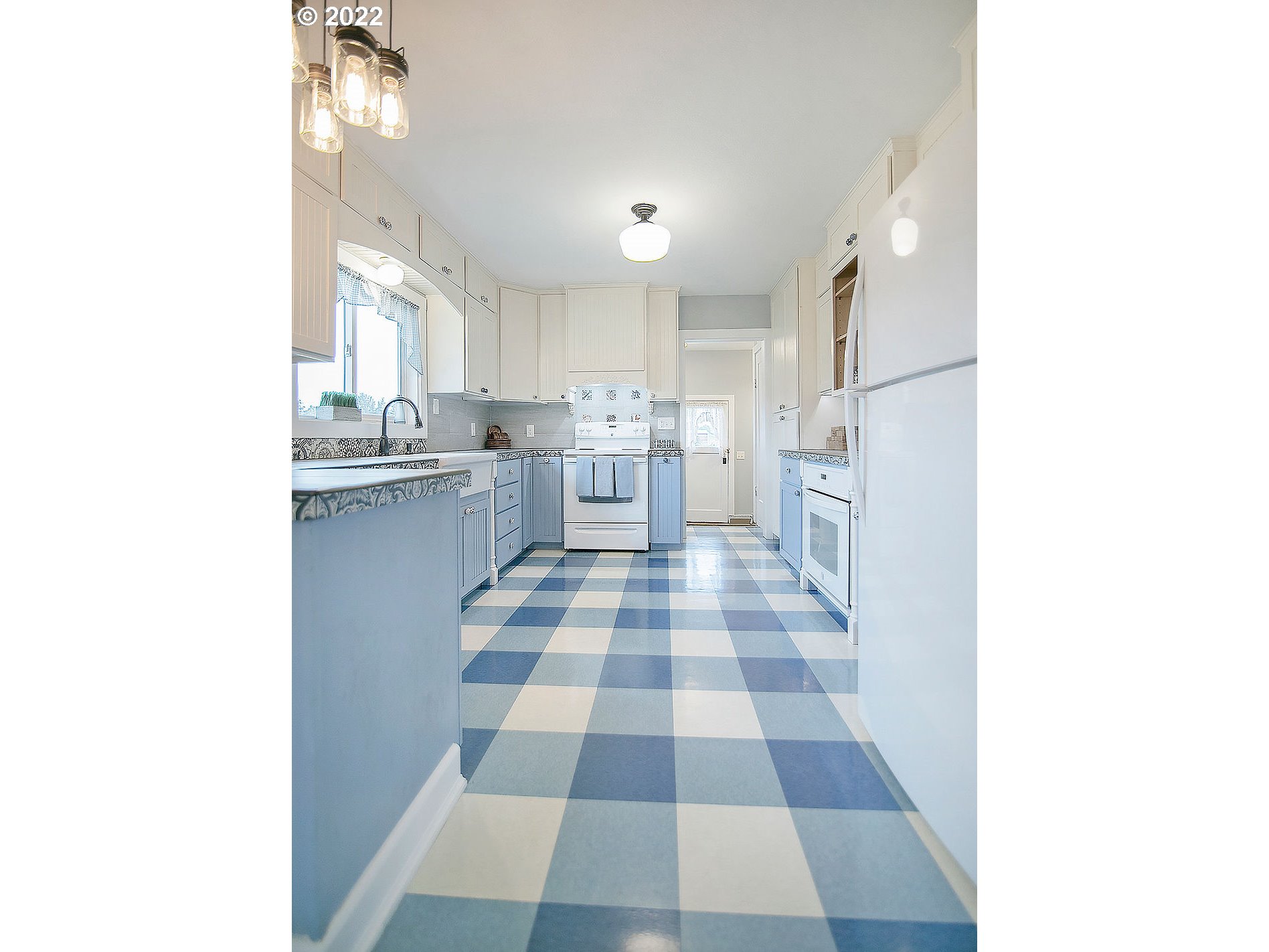 121 Rarey Road Winlock, WA 98596 - Photo 9 of 32 a kitchen with a checkered floor and white cabinets