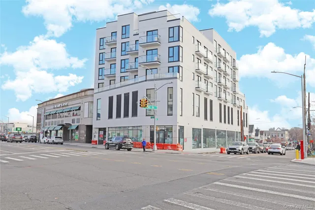 a front view of a building with lot of cars and trees