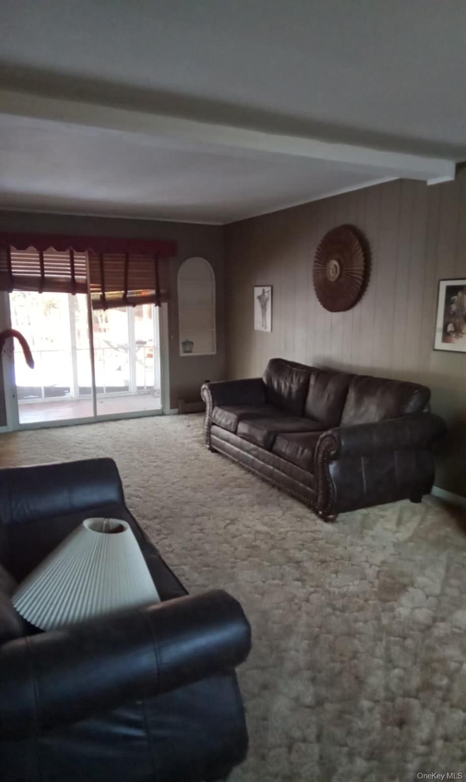 88 Barnes Road Blooming Grove, NY 10992 - Photo 5 of 12 Carpeted living room featuring beamed ceiling and wooden walls