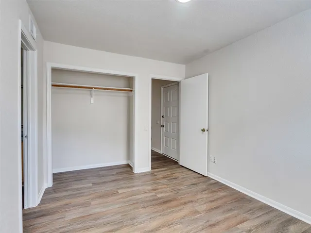 a view of an empty room with wooden floor & closet