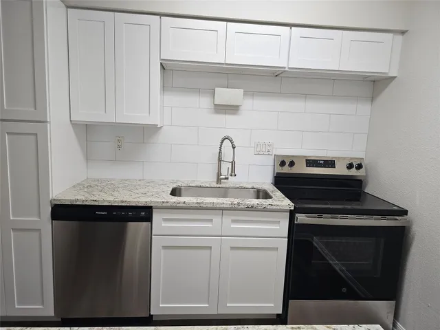 a kitchen with white cabinets and sink