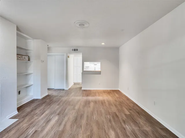 a view of empty room with wooden floor and window