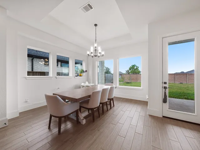 a dining room with wooden floor a chandelier a wooden table and chairs