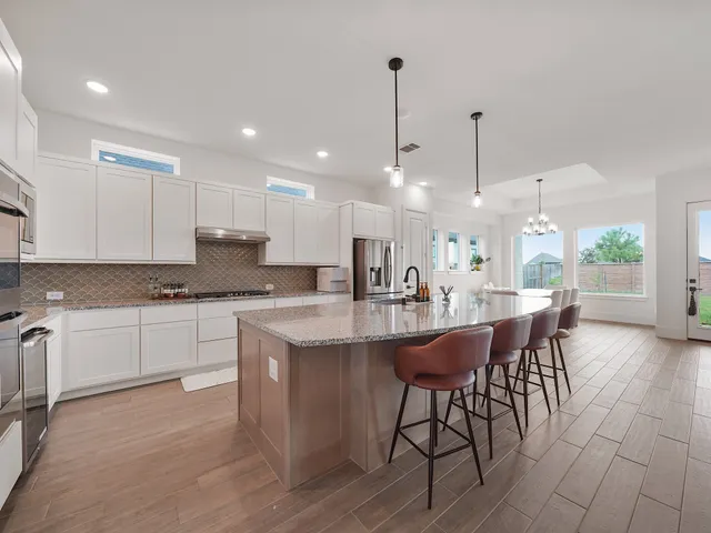 a kitchen with stainless steel appliances kitchen island granite countertop a table chairs sink and cabinets