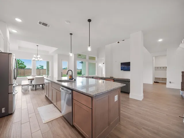 a kitchen with stainless steel appliances granite countertop a sink a stove and a wooden floor