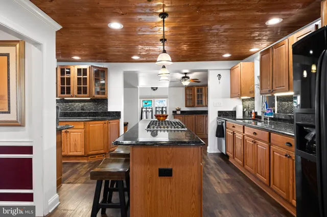 a kitchen with kitchen island granite countertop lots of counter top space and wooden floor