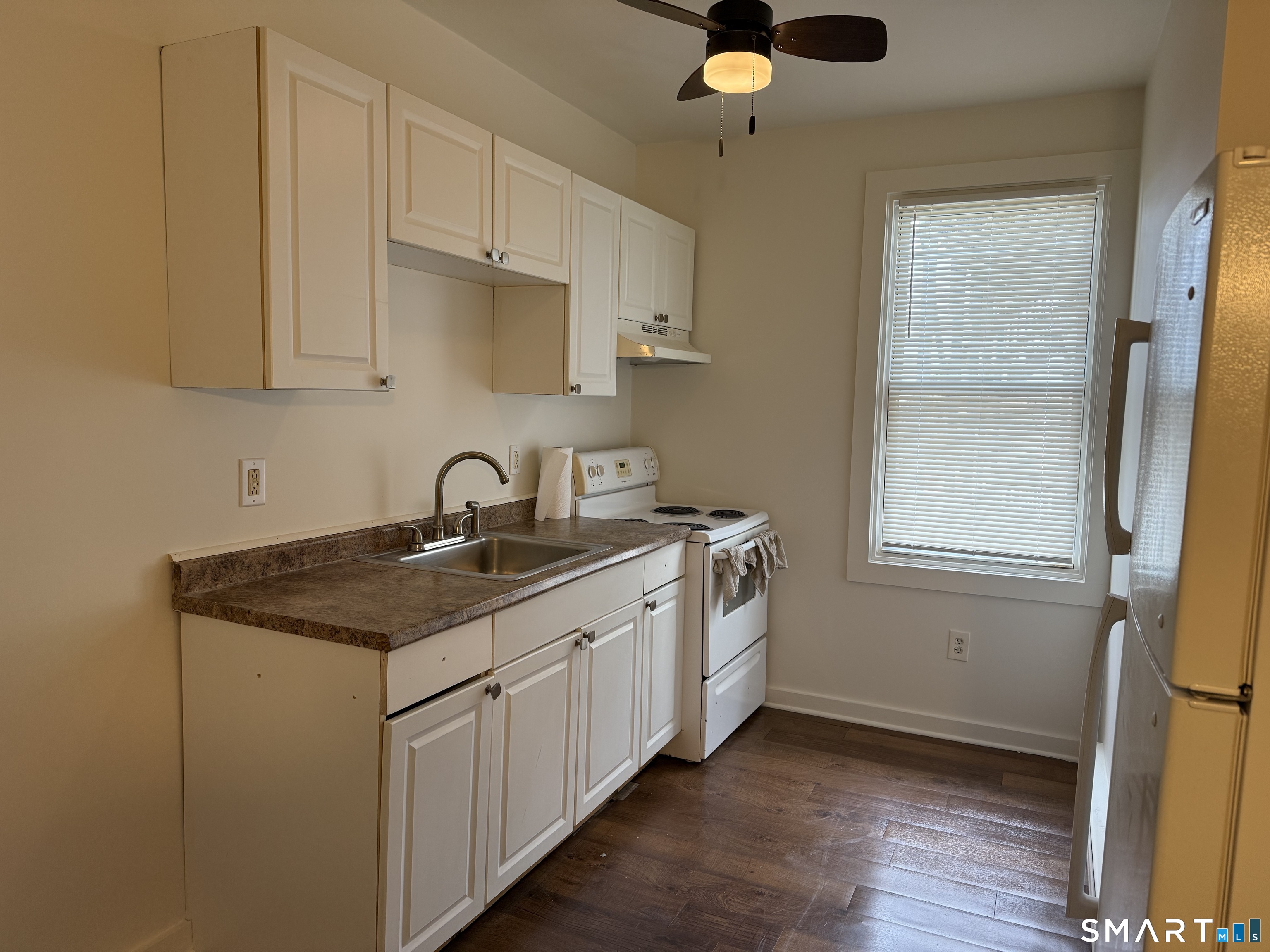 837 Bank Street, Unit 3 New London, CT 06320 - Photo 2 of 5 a kitchen with stainless steel appliances granite countertop a sink stove and white cabinets with wooden floor