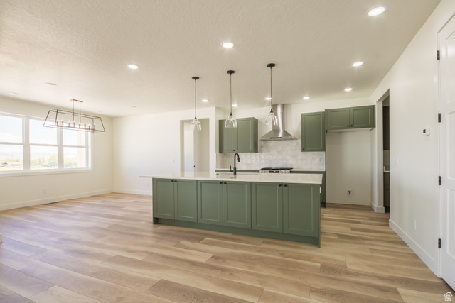 3322 250 S Street Vernal, UT 84078 - Photo 5 of 37 Kitchen featuring olive green cabinetry, a central island with a light-toned countertop, a stainless steel range hood, and a white subway tile backsplash
