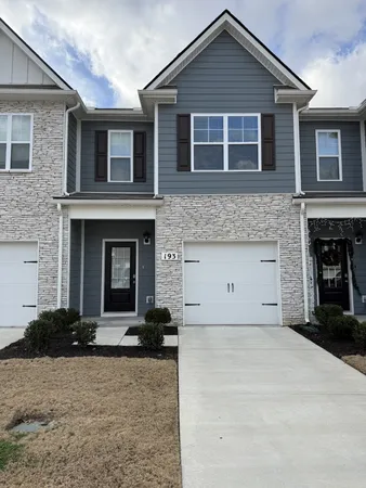 a front view of a house with yard and parking