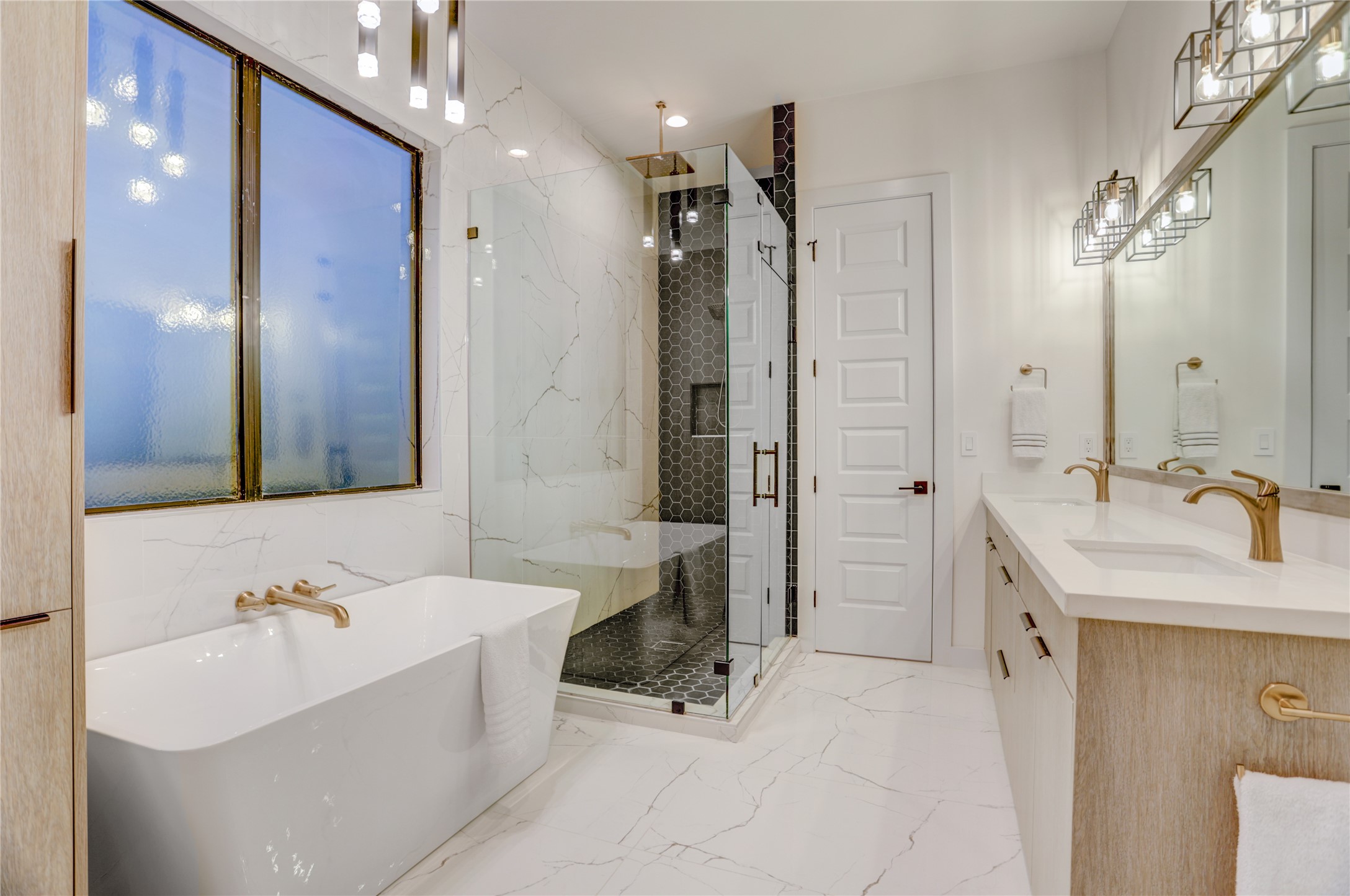 2435 Sheridan Street Houston, TX 77030 - Photo 15 of 25 Luxurious primary bathroom featuring a sleek glass shower, elegant soaking tub, dual sinks, and modern lighting for a spa-like retreat.