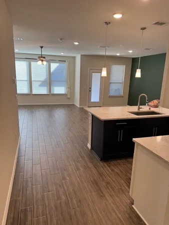 a room with kitchen island sink and wooden floor