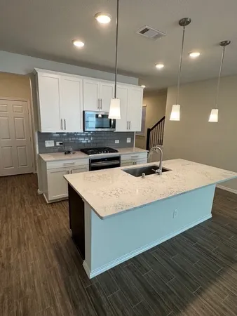 a kitchen with kitchen island granite countertop a sink a counter space appliances and cabinets