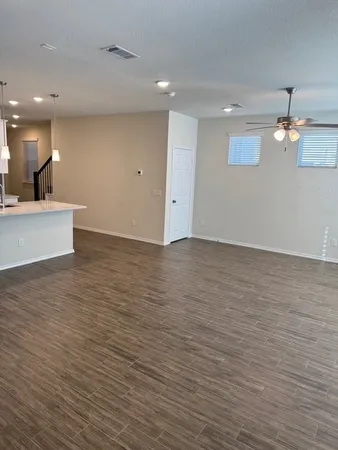 a view of kitchen and empty room with wooden floor