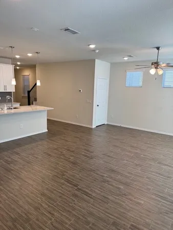 a view of kitchen and empty room with wooden floor
