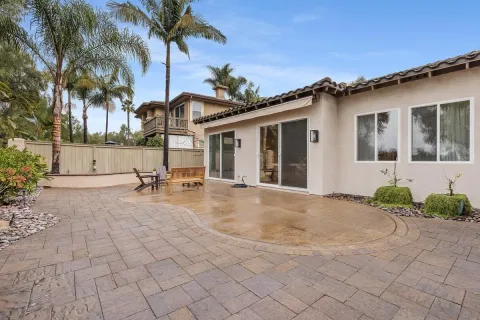 a view of a white house with a yard and coconut trees