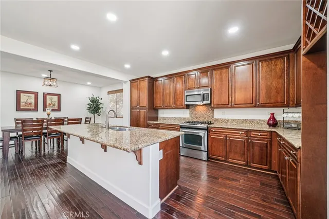 a large kitchen with stainless steel appliances granite countertop plenty wooden cabinets counter space and wooden floor