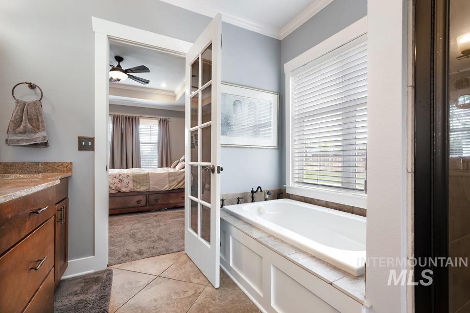 8271 Washoe Road Fruitland, ID 83619 - Photo 21 of 29 Bathroom featuring a built-in soaking tub with tiled surround, a vanity with stone-finish countertop, and tile flooring