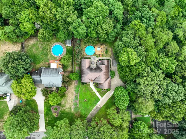 an aerial view of a house with a swimming pool a yard and a fountain