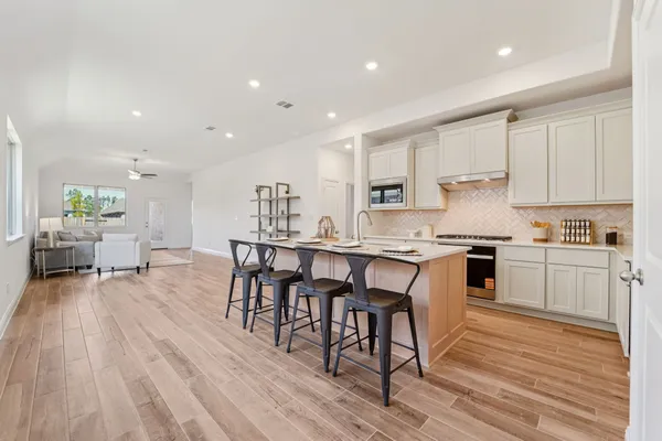 a kitchen with a table chairs wooden floors and view living room