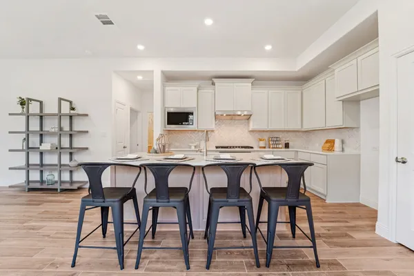 a kitchen with stainless steel appliances granite countertop a table chairs microwave and sink