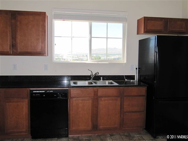 9050 Double R Boulevard Reno, NV 89511 - Photo 7 of 13 a kitchen with granite countertop a refrigerator and a sink
