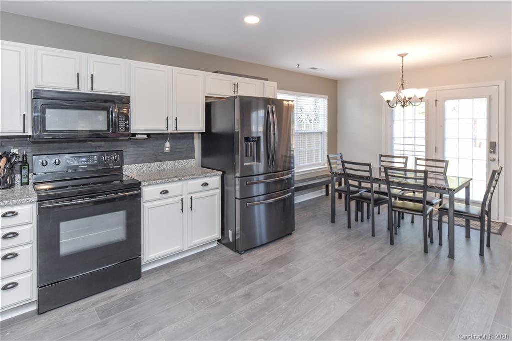 717 Jones Branch Road Fort Mill, SC 29715 - Photo 7 of 31 a kitchen with stainless steel appliances granite countertop a stove a refrigerator a microwave a dining table and chairs with wooden floor