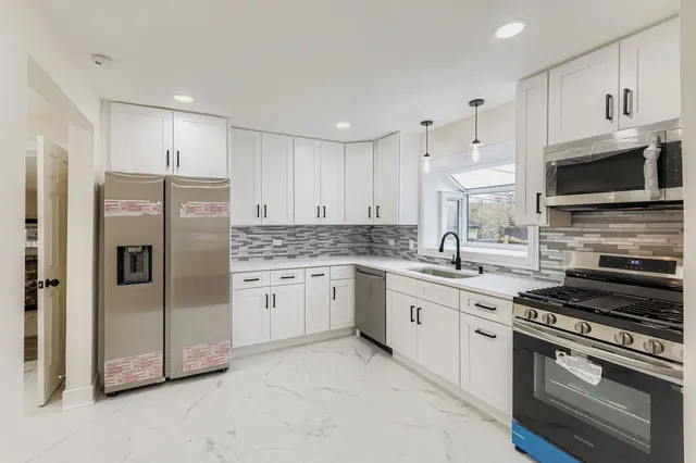 a kitchen with granite countertop a refrigerator stove and microwave