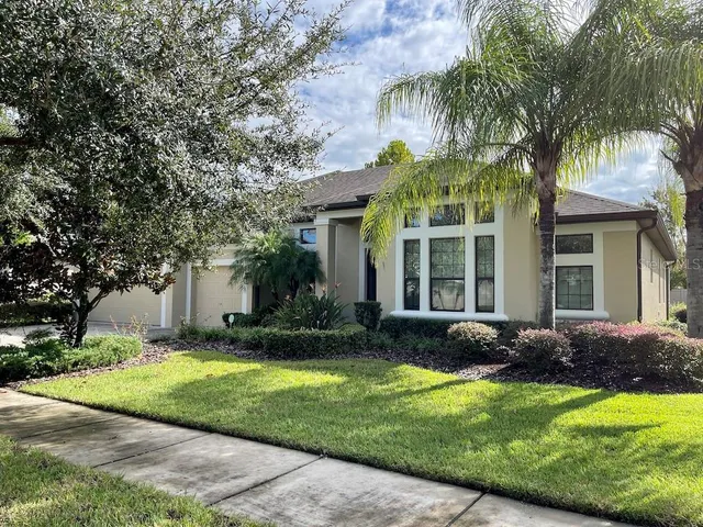 a view of a house with a yard and palm trees