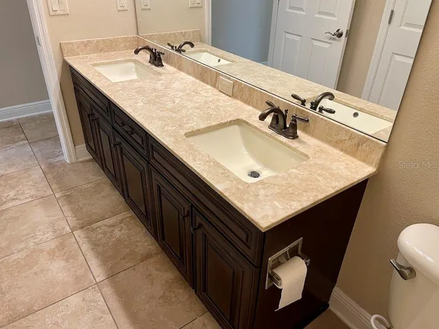 a bathroom with a granite countertop sink and a toilet