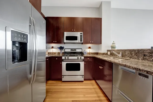 a kitchen with stainless steel appliances granite countertop a stove a sink and a microwave