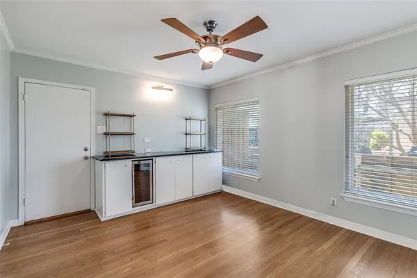 an empty room with wooden floor a ceiling fan and windows