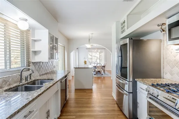 a kitchen with granite countertop a sink stove and refrigerator