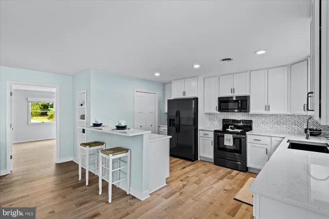 a kitchen with a refrigerator a stove top oven a sink dishwasher and white cabinets with wooden floor