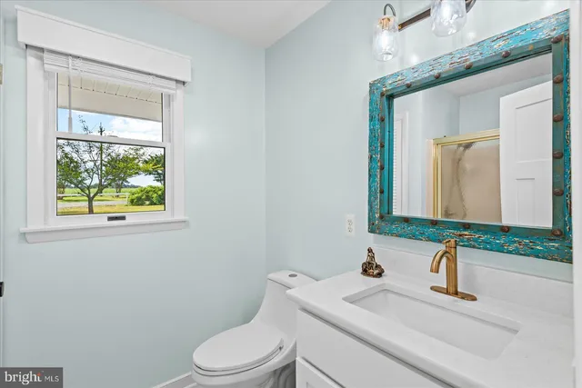 a bathroom with a granite countertop sink vanity mirror and toilet