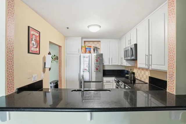 a kitchen with stainless steel appliances granite countertop a sink and a refrigerator