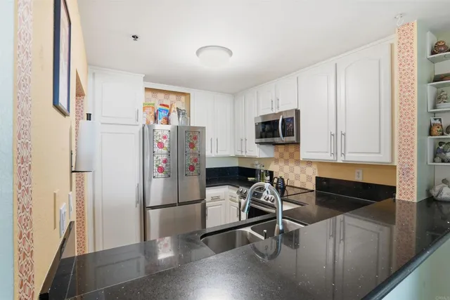 a kitchen with stainless steel appliances granite countertop a refrigerator and a stove top oven
