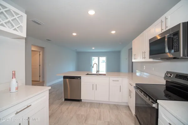 a kitchen with granite countertop a sink dishwasher stove and microwave with wooden floor