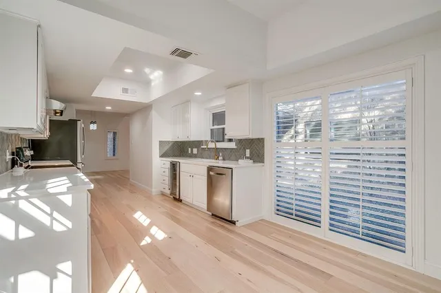 a kitchen with granite countertop a stove a sink and white cabinets with wooden floor