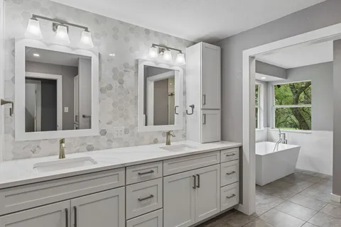 a bathroom with a double vanity sink large mirror and a bathtub