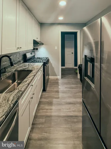 a kitchen with granite countertop a refrigerator and a sink