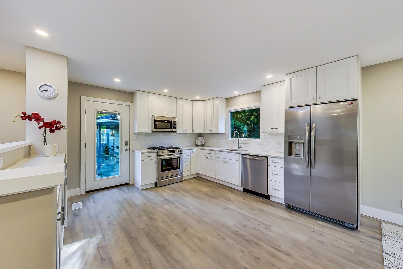 443 Raupp Boulevard Buffalo Grove, IL 60089 - Photo 4 of 21 a large kitchen with a refrigerator a oven a sink dishwasher and white cabinets with wooden floor